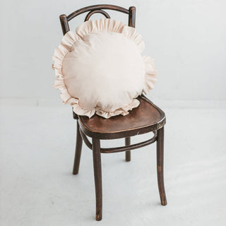 The cushion displayed on chair, its ruffled trim adding texture and elegance to a stylish living room