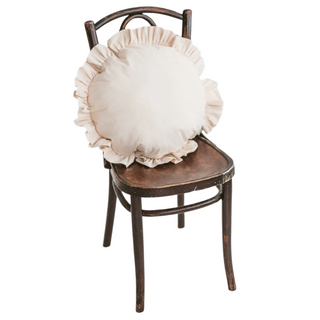 A beige round cushion with ruffled trim